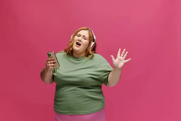 A woman sings along to music while holding a smartphone. — Stock Photo