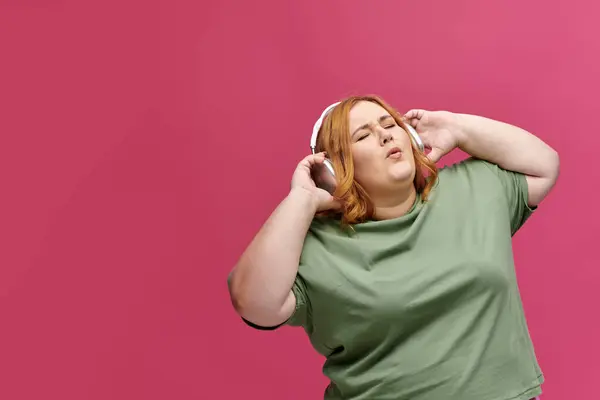 A woman wearing headphones dances with her eyes closed. — Stock Photo