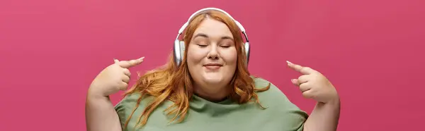 Una mujer de talla grande sonríe mientras escucha música con auriculares. — Stock Photo