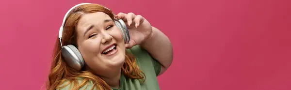 Una donna plus size sorride e canta con le cuffie. — Foto stock