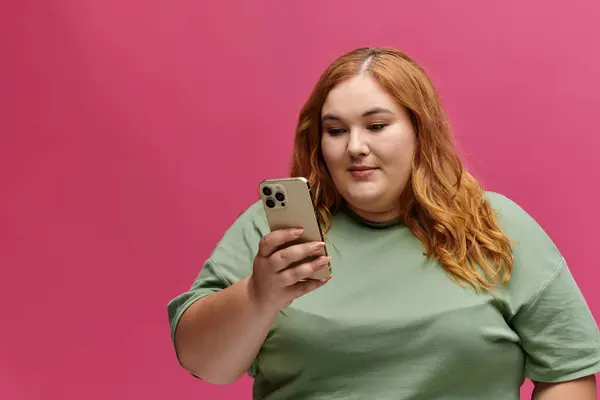 A woman in a green t-shirt looks intently at her phone, her expression focused. — Stock Photo