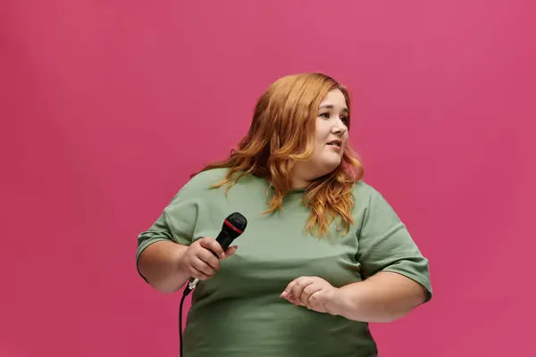 Eine Frau mit roten Haaren hält ein Mikrofon in der Hand, bereit zu singen. — Stockfoto