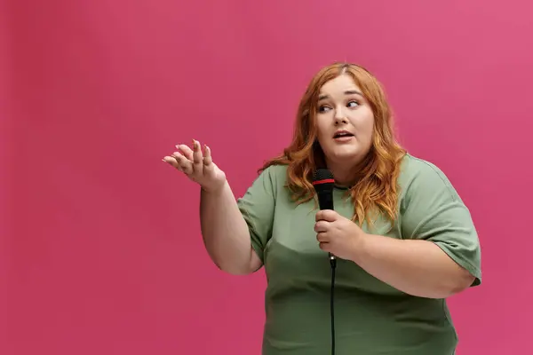 Una donna plus-size parla in un microfono con uno sfondo rosa. — Foto stock