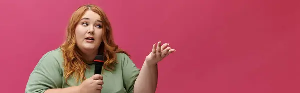 Woman with red hair holding microphone speaks with conviction and gestures right — Stock Photo