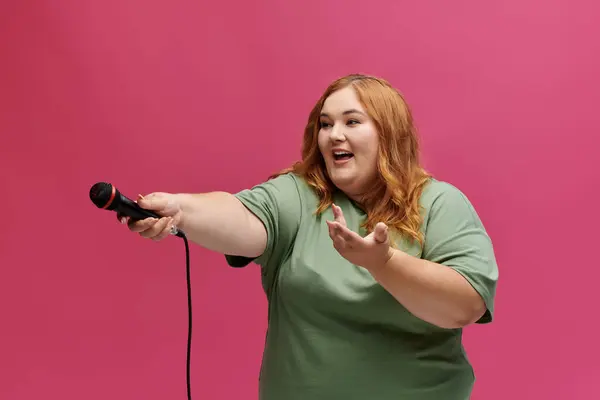 A woman in a green t-shirt holds a microphone and speaks animatedly. — Stock Photo