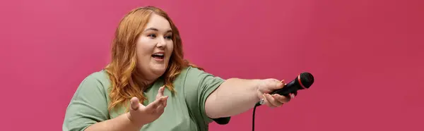 Una donna canta in un microfono, sorridendo e gesticolando con l'altra mano. — Foto stock