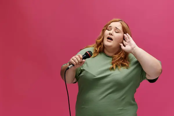 Una donna con i capelli rossi canta in un microfono, con la mano cucita dietro l'orecchio. — Foto stock