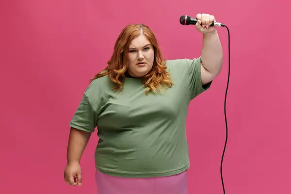 Eine Frau mit roten Haaren hält ein Mikrofon in der Hand und singt mit selbstbewusster Miene. — Stockfoto