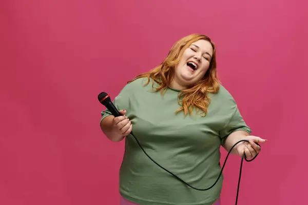 Una donna ride gioiosa mentre tiene in mano un microfono. — Foto stock