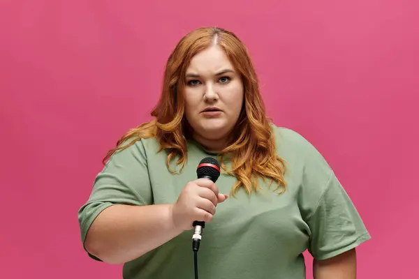 A plus size woman with red hair holds a microphone and speaks into it. — Stock Photo