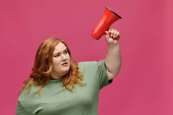 A confident woman with red hair holds a megaphone, looking determined. — Stock Photo