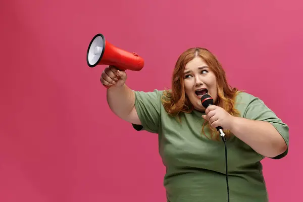 Una donna canta in un microfono mentre tiene un megafono. — Foto stock