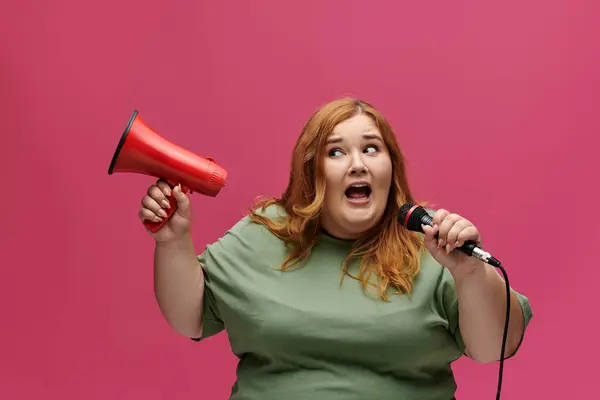 Женщина plus size уверенно держит мегафон и микрофон, готовая сделать свой голос услышанным. — стоковое фото