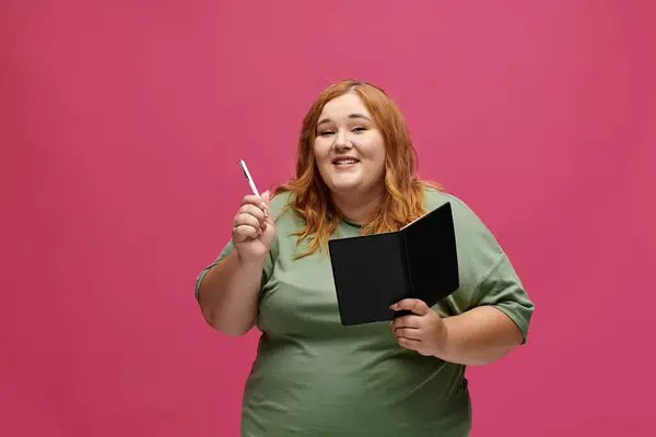 Eine Frau lächelt selbstbewusst und hält Stift und Notizbuch in der Hand. — Stockfoto