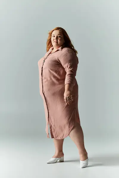 Una mujer en un vestido largo y rosa está de pie con confianza y estilo. - foto de stock