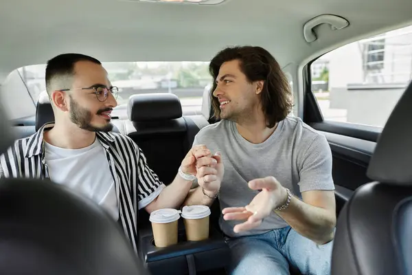 Ein schwules Paar lächelt und unterhält sich auf dem Rücksitz eines Autos bei einem Kaffee-Date. — Stockfoto