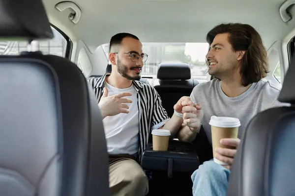 A gay couple enjoys coffee together in the backseat of a car. — Stock Photo