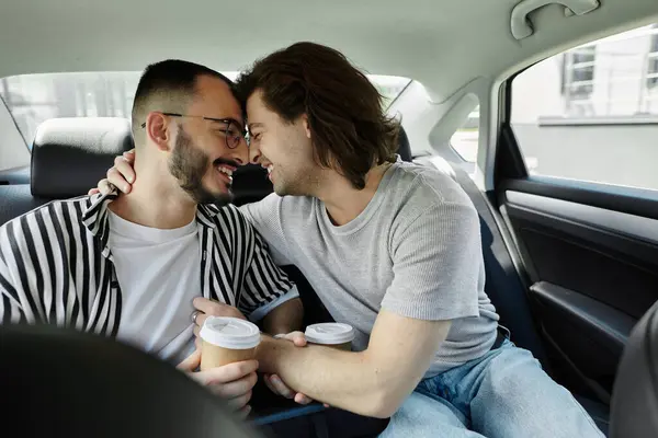 Two men are sitting in a car, holding hands and smiling at each other. — Stock Photo