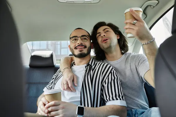 Two men in the back seat of a car, smiling and enjoying coffee. — Stock Photo