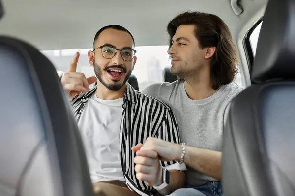Two men hold hands in the backseat of a car, smiling and laughing. — Stock Photo