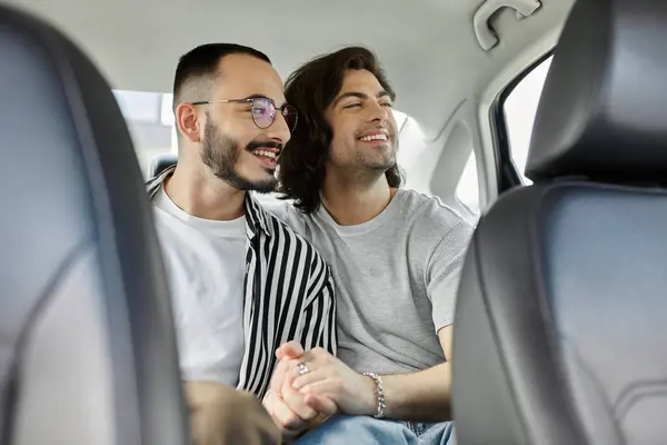Two men hold hands and smile while riding in a car. — Stock Photo