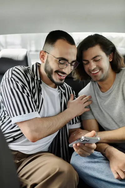 Two men in a car, laughing and looking at a phone. — Stock Photo