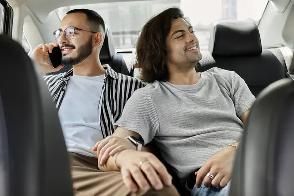 Two men hold hands while riding in a car. — Stock Photo