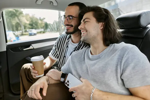 A gay couple enjoy a coffee date in the backseat of a car. — стоковое фото