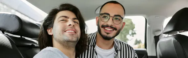 A loving gay couple smiles at each other in the backseat of a car. — Stock Photo