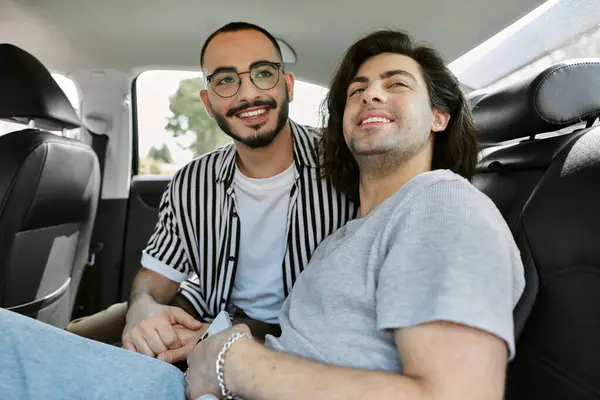 A gay couple smiles and holds hands while riding in a car. — Stock Photo