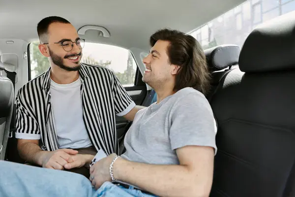 Two men, dressed casually, smile and laugh together in a car. — Stock Photo