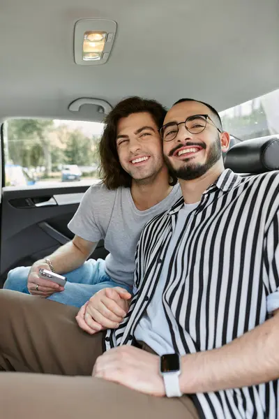 A gay couple smiles for a photo in the backseat of a car. — Stock Photo