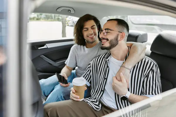 A gay couple shares a coffee and affectionate moment in the backseat of a car. — Stock Photo