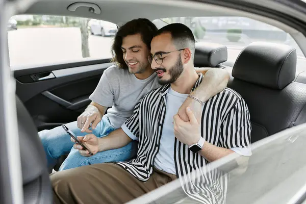 Two men in the backseat of a car, one holds his partner and looks at the phone. — Stock Photo
