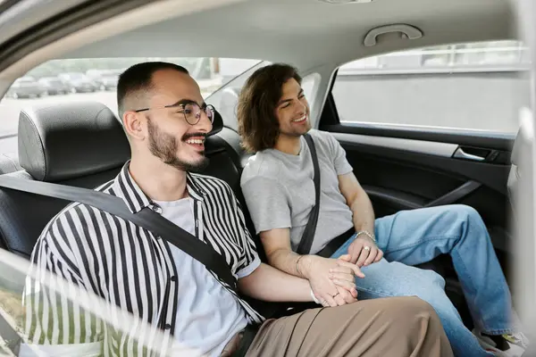 A gay couple smiles and holds hands while riding in a car. — Stock Photo