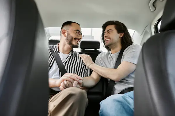 Two men sit in the backseat of a car, laughing and holding hands. — Stock Photo