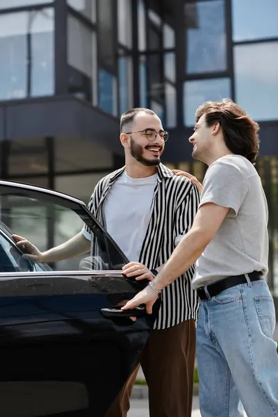 A gay couple laughs together as one opens the car door. — Stock Photo