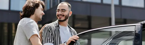 A gay couple laughs together while getting into a car. — Stock Photo
