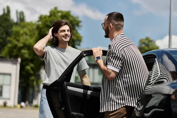 Two men stand beside a car, smiling and talking. — Stock Photo