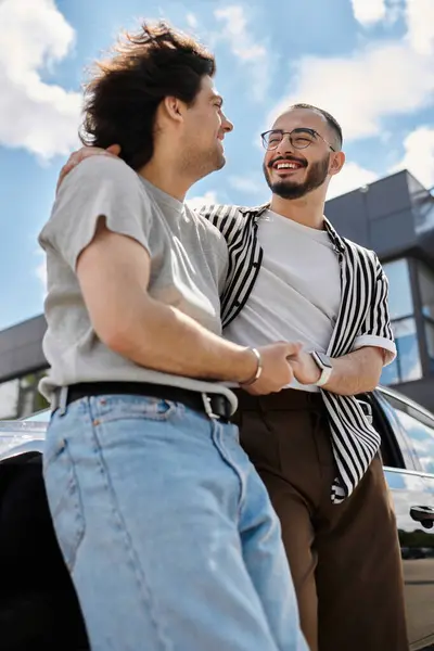 Two men in love, standing beside a car, laughing and sharing a tender embrace. — Stock Photo