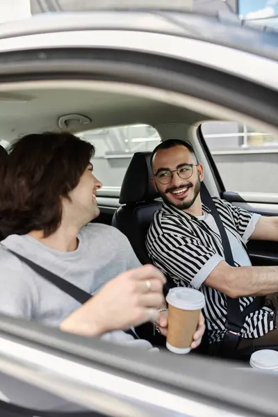 Two men smile at each other while driving in a car. — Stock Photo