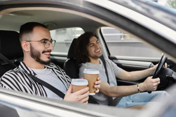 A gay couple enjoys coffee together in a car. — Stock Photo