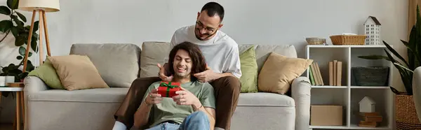 A gay couple enjoys a special moment together, one man presenting a gift to the other. — Stock Photo