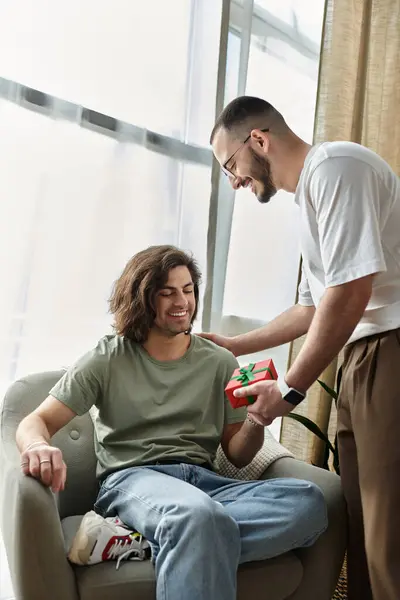 A man gives his partner a gift in their living room. — Stock Photo