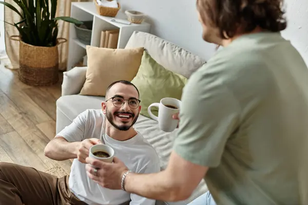 A loving gay couple shares a moment of joy and intimacy over a cup of coffee. — Stock Photo