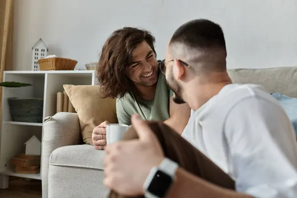 Un couple gay aime le café et la compagnie de l'autre sur un canapé confortable. — Photo de stock