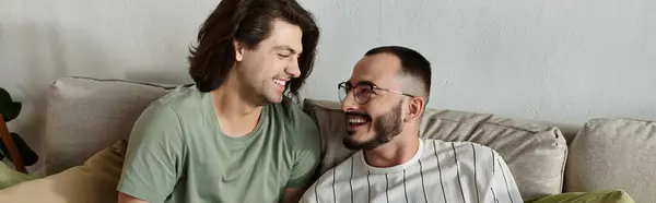 Two men, a couple, laugh together on a couch, sharing a moment of joy and connection. — Stock Photo