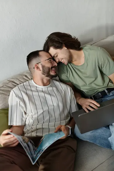 Dois homens se abraçam em um sofá, sorrindo e gostando da companhia um do outro. — Fotografia de Stock