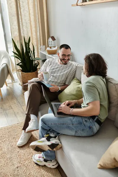 Gay couple shares cozy afternoon with coffee and laptop on couch — Stock Photo
