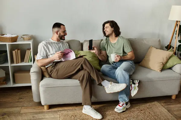 A gay couple relaxes on a couch, laughing and enjoying each other's company. — Stock Photo